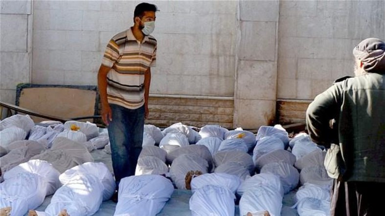 A rescue worker stands amid rows of dead bodies which had suffered sarin exposure. Ghouta, Damascus, August 21, 2013