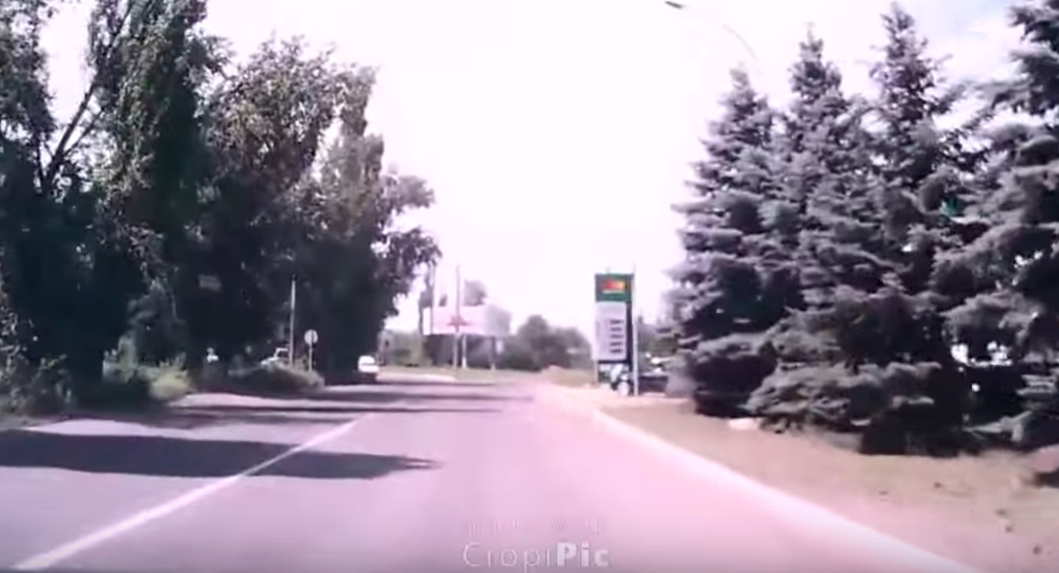 View from video, in which the fuel station, roundabout, and lines of trees are all visible